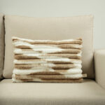 Coussin beige et blanc en fausse fourrure