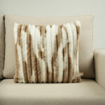 Coussin beige et blanc en fausse fourrure